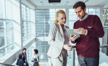 Businesspeople talking to each other and using technology during their office break